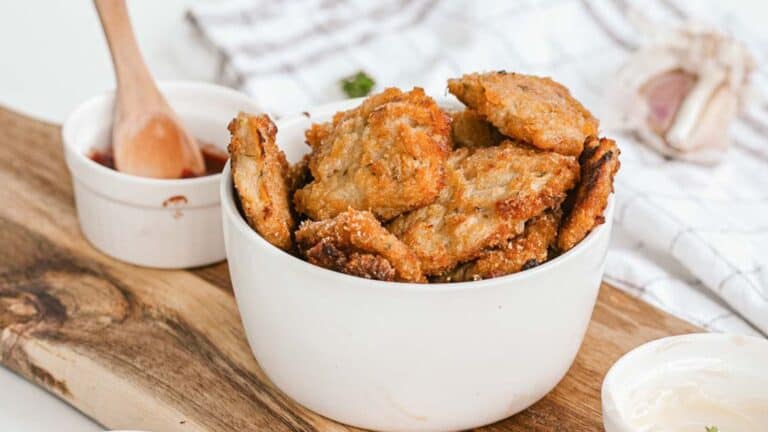 Fried tofu in a white bowl on a cutting board.