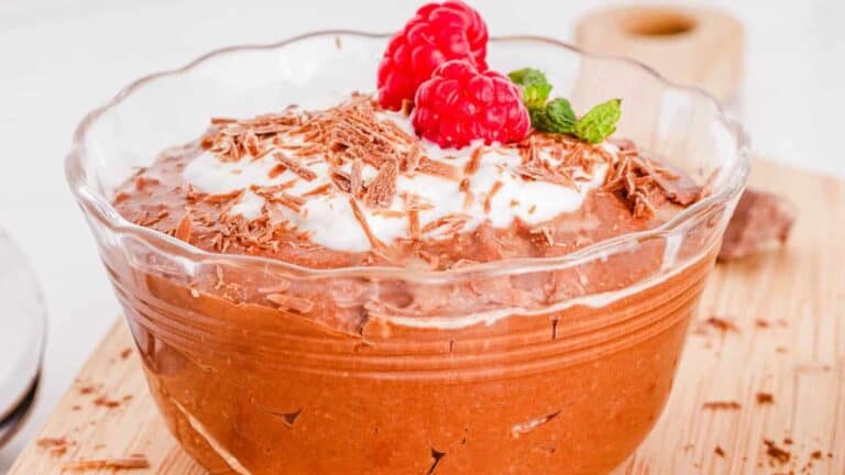 Chocolate mousse in a glass with raspberries and whipped cream.