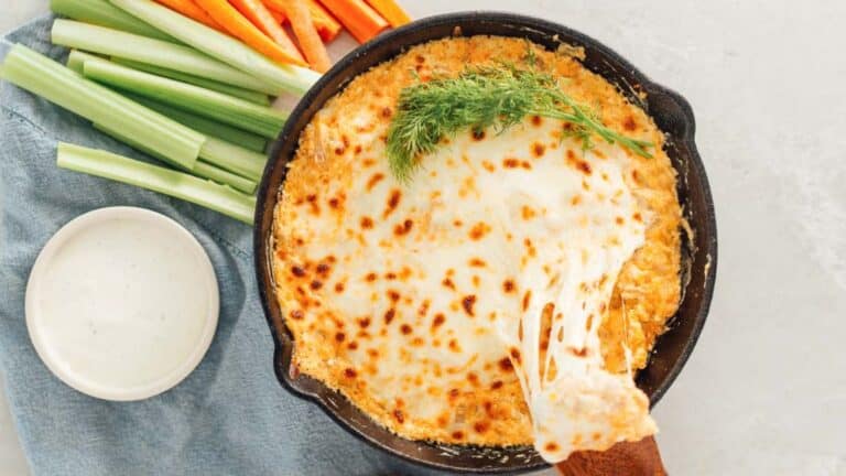 A skillet of food with a spoon and a plate of carrots and celery.