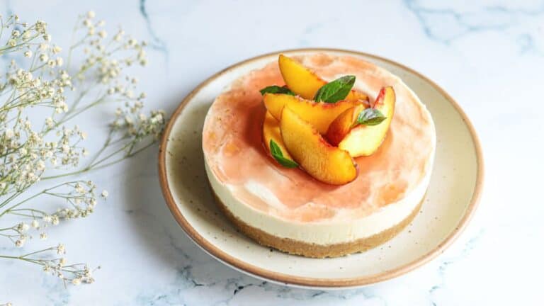 Peach cheesecake on a white plate with flowers.