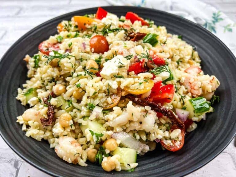 A bowl of Mediterranean orzo salad on a black plate.