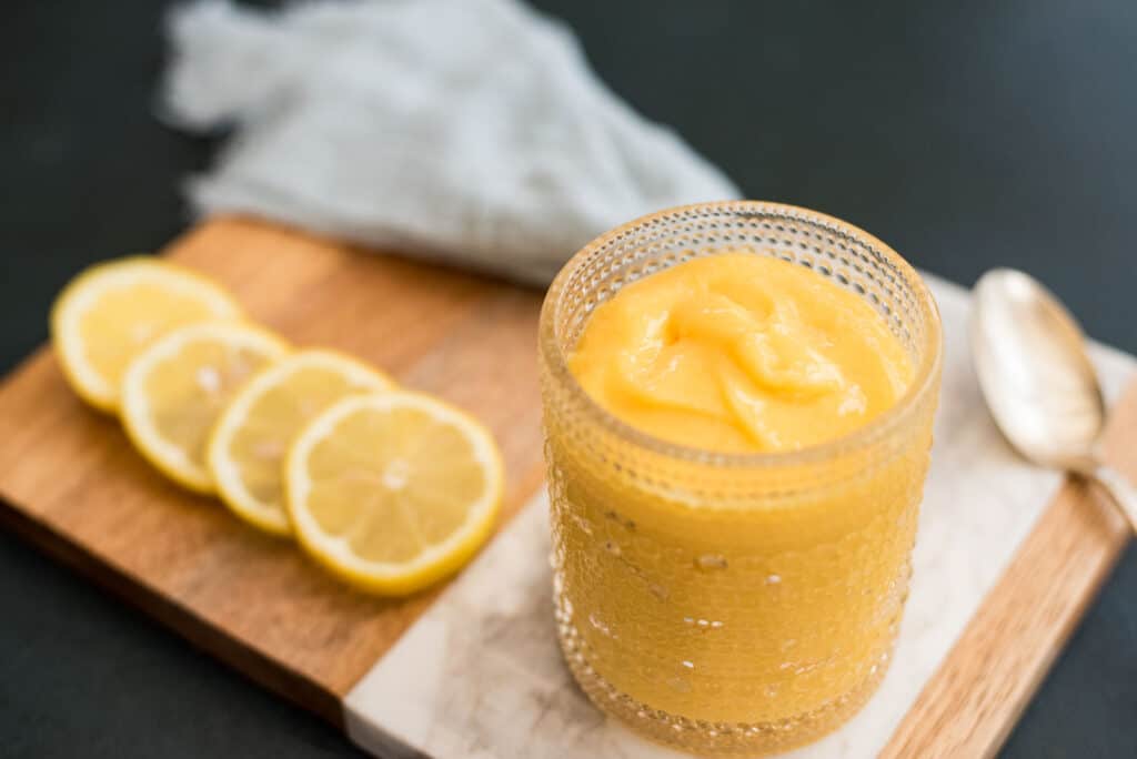 Scones on a plate next to a meyer lemon curd in a jar and smeared on a plate. 