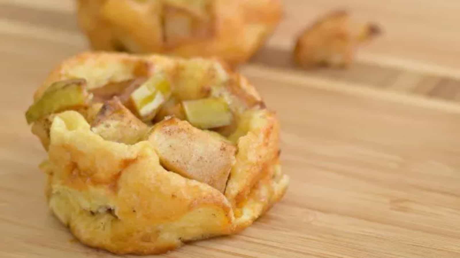 Image shows a close up of a Mini Apple Pancake with more in the background sitting on a wooden table.