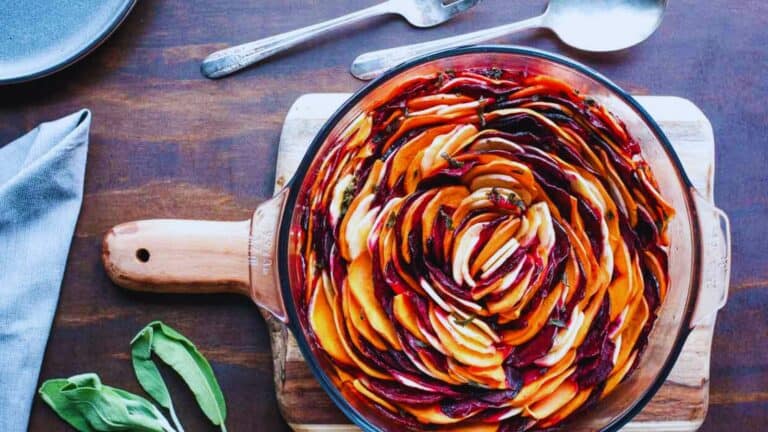 A dish with sliced beets and sprigs of sage.