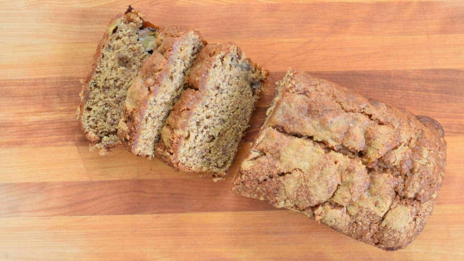 Overhead of brown sugar banana bread partially sliced on a cutting board.