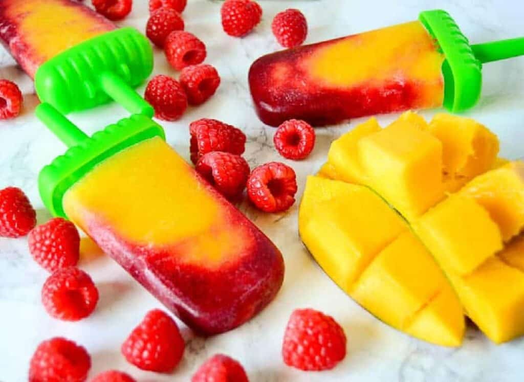 Mango popsicles with raspberries and mangoes.