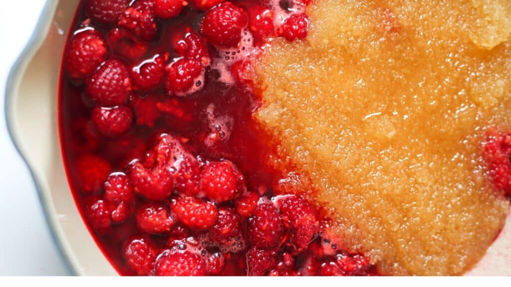 A dish with raspberries and sugar in it.