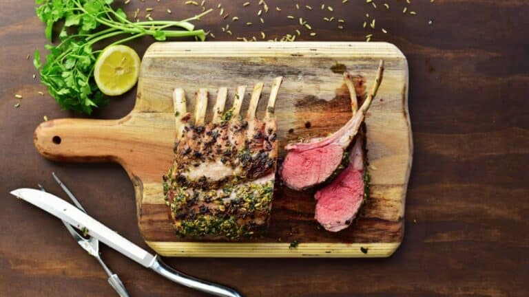 Grilled rack of lamb on a wooden cutting board.