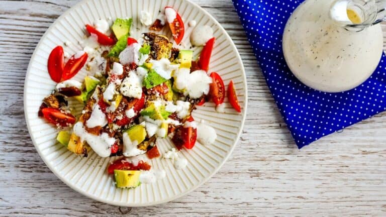 A plate with a roasted cabbage steak salad and a bottle of dressing.