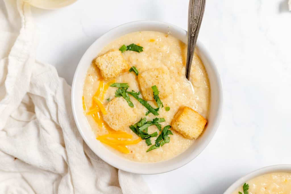 A bowl of soup with croutons and parmesan cheese.