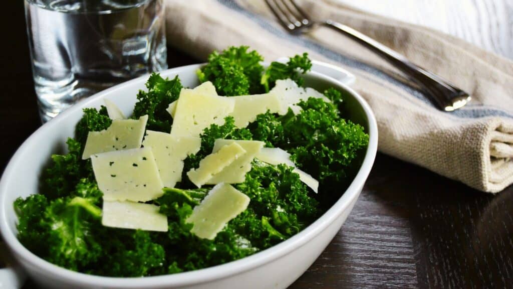 A bowl of kale salad with shaved parmesan cheese.