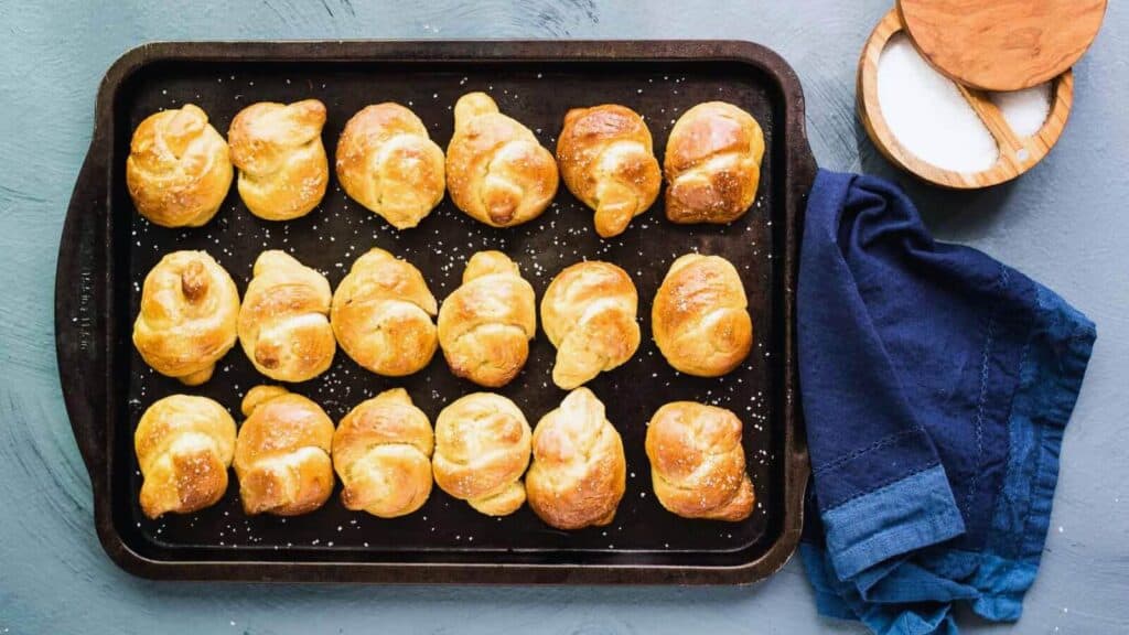 Pretzel knots on a baking tray on a blue background.