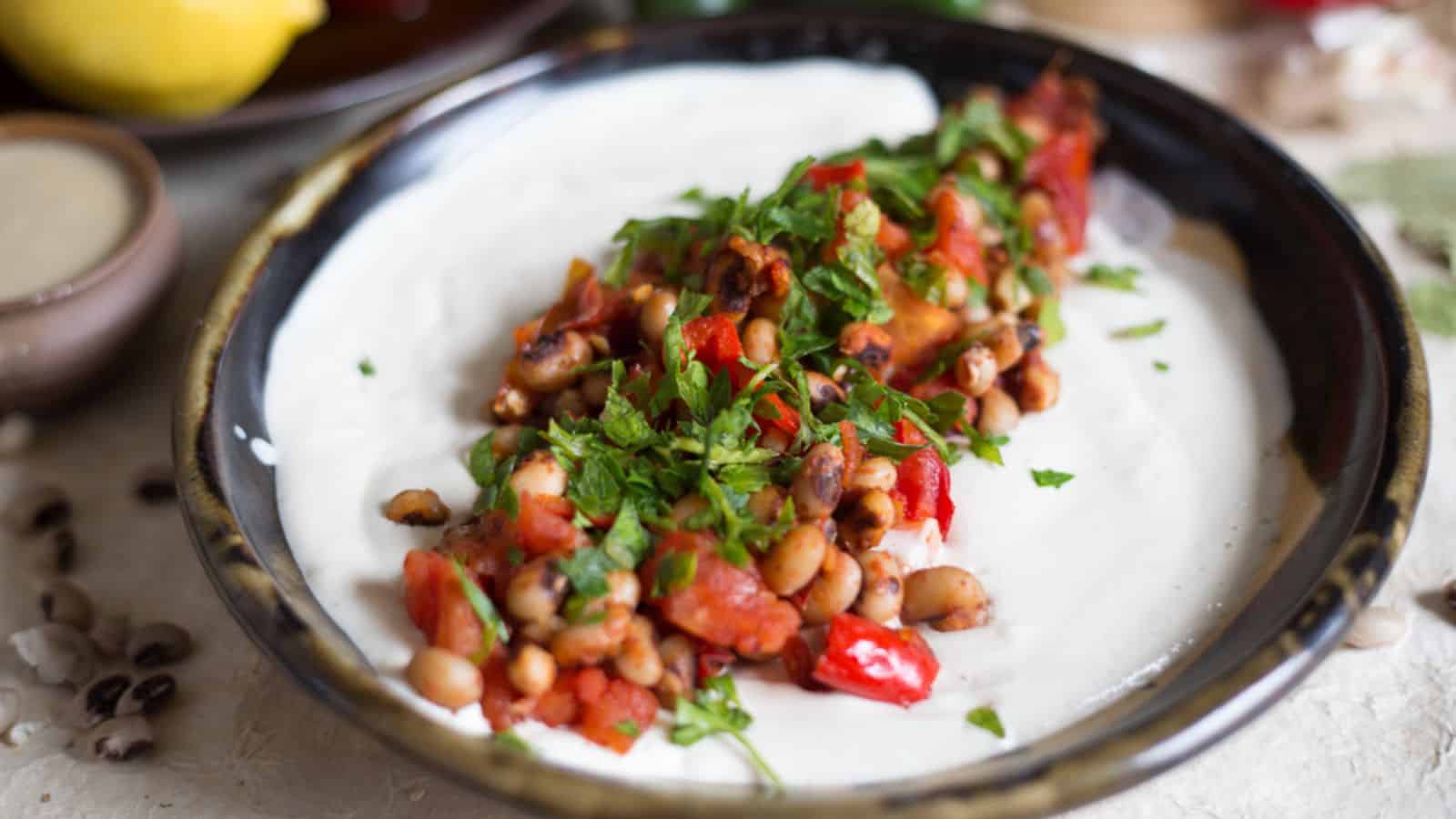 A bowl of black beans and yogurt on a table.