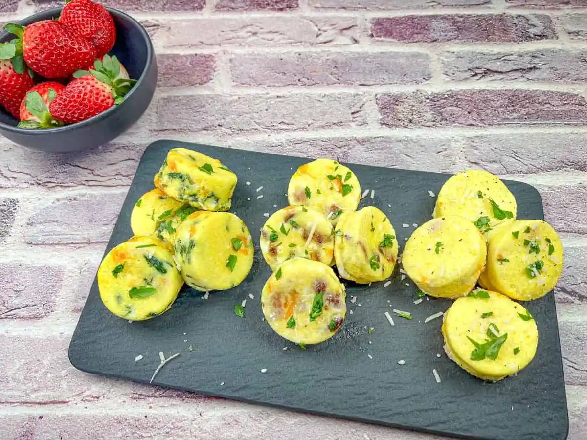 Egg bites with spinach & cheese on a black plate.