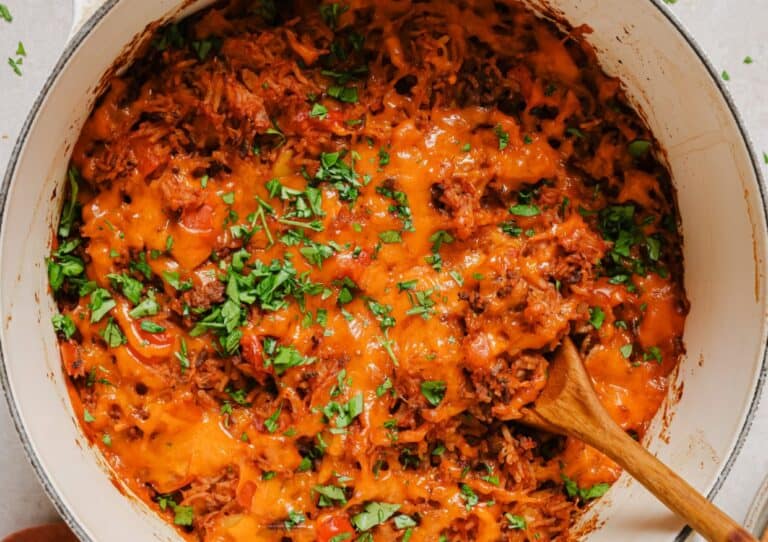 Stuffed bell pepper casserole in a pan with a wooden spoon.