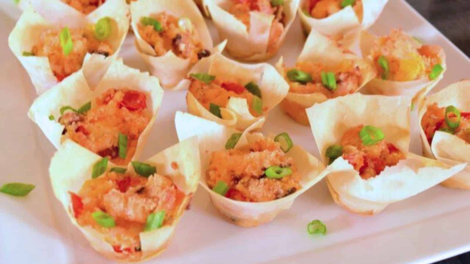 Image shows  A plate of tomato bacon cup appetizers on a white plate.