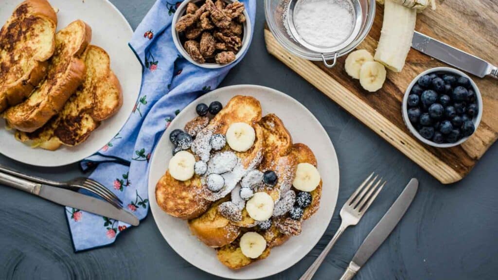 A plate of french toast with bananas, blueberries and nuts.