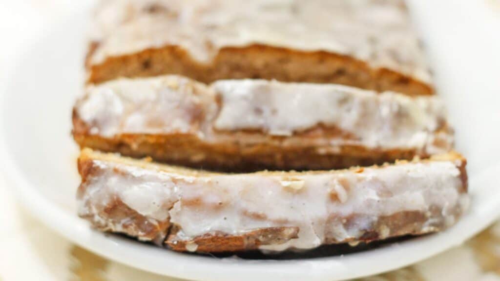 A slice of banana bread with icing on a plate.