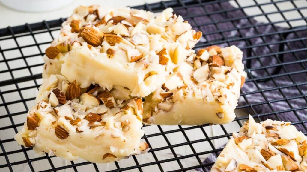 A close up of food white chocolate fudge on a black wire rack. 