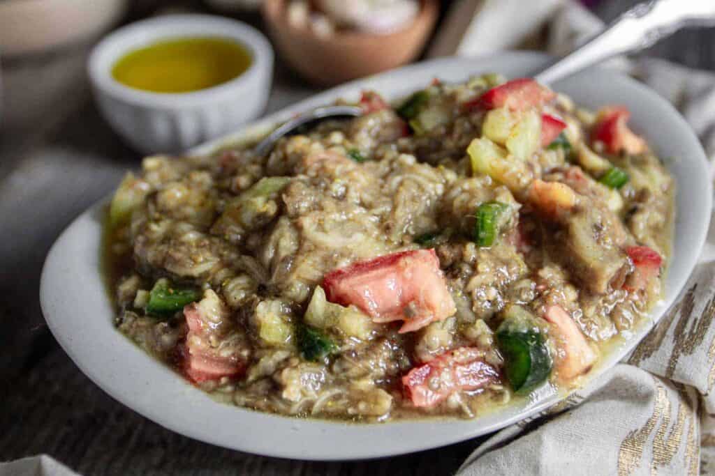 A bowl of food on a table next to a spoon.