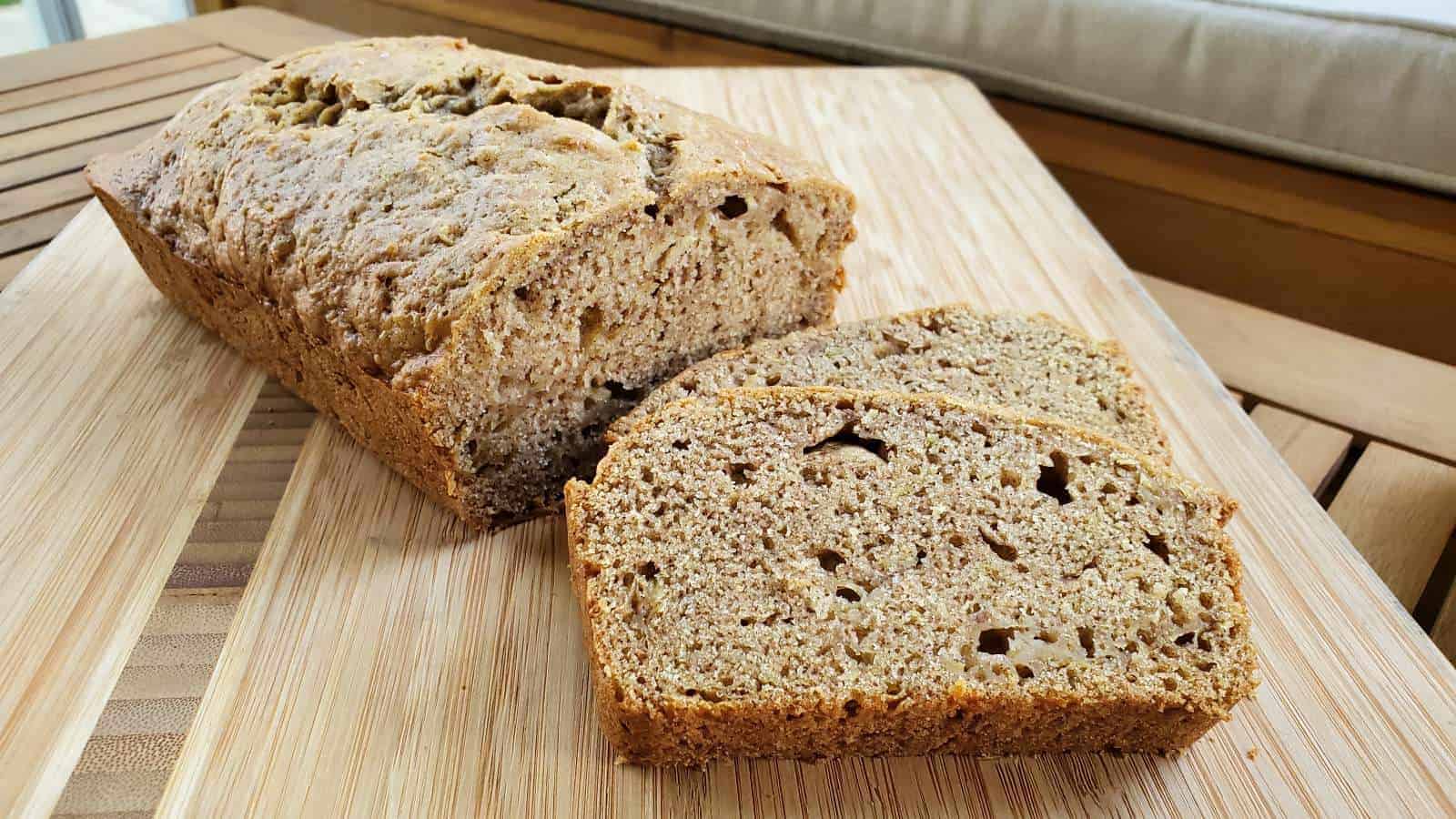 Zucchini bread loaf with slices on a cutting board.