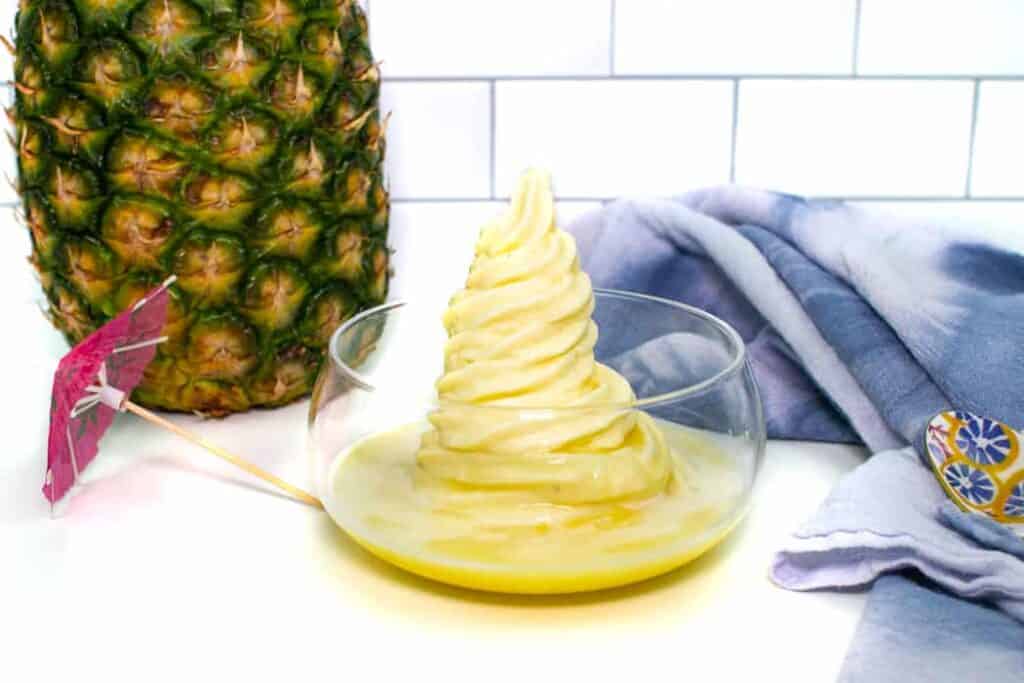 A bowl of pineapple ice cream next to a pineapple.