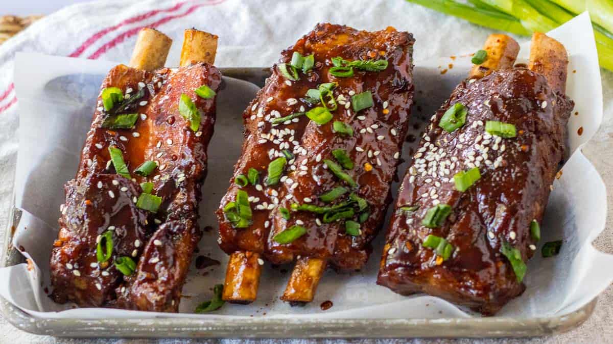 Two ribs on a tray with sesame seeds and green onions.