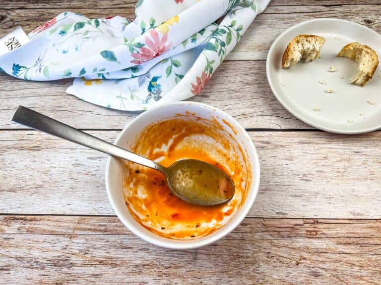 A bowl of soup with a spoon and a plate of bread.