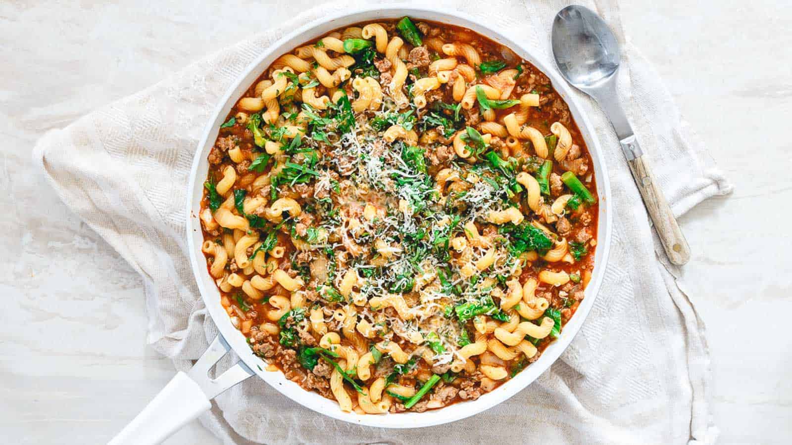 Lamb ragu with cavatappi pasta in a white skillet.