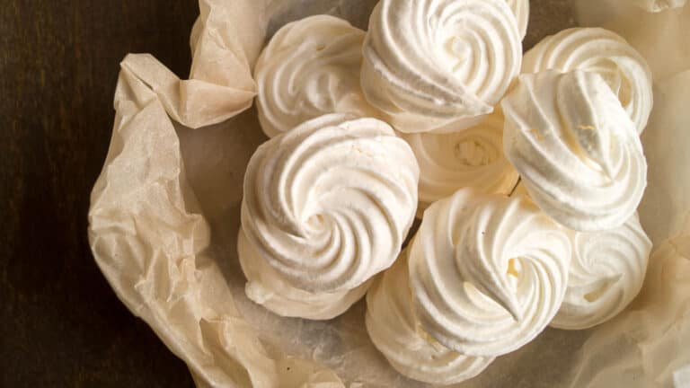 Meringue in a paper bag on a wooden table.