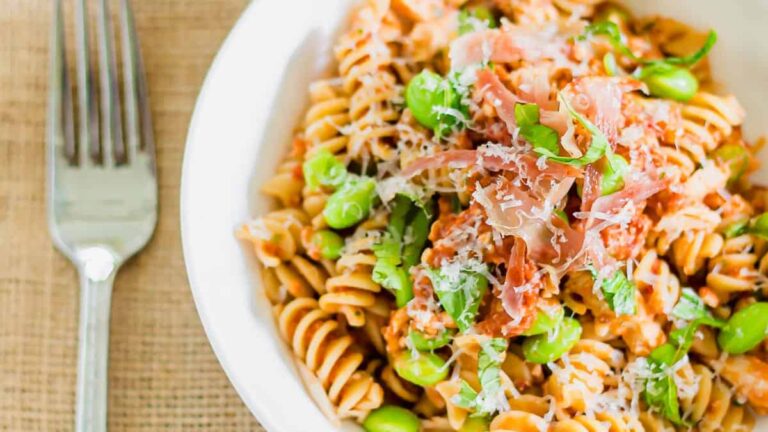 A bowl of pasta with peas and prosciutto.