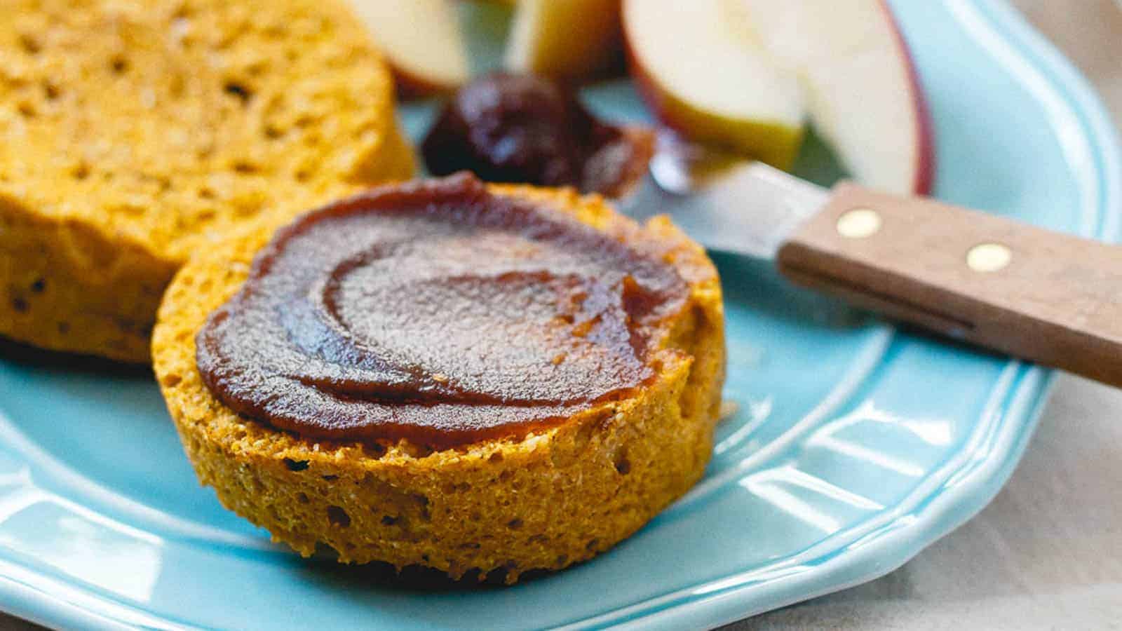 Pumpkin english muffins on a blue plate with apple butter spread on one half.