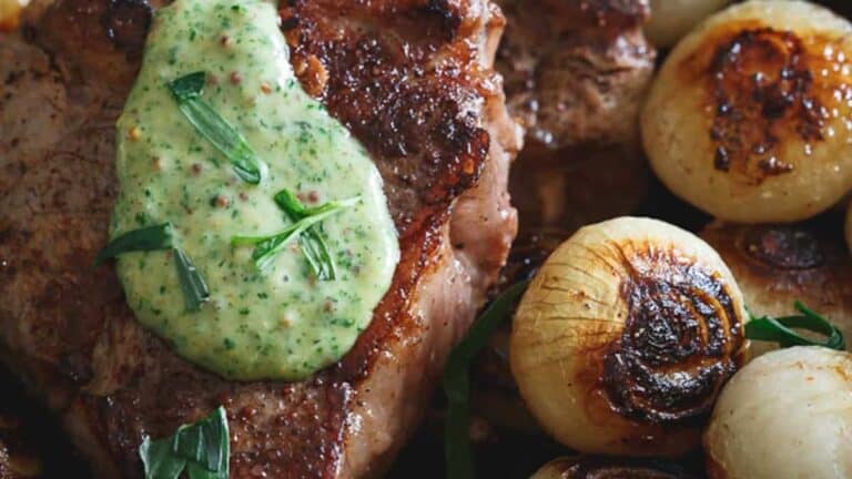 A steak with green sauce and onions on a plate.