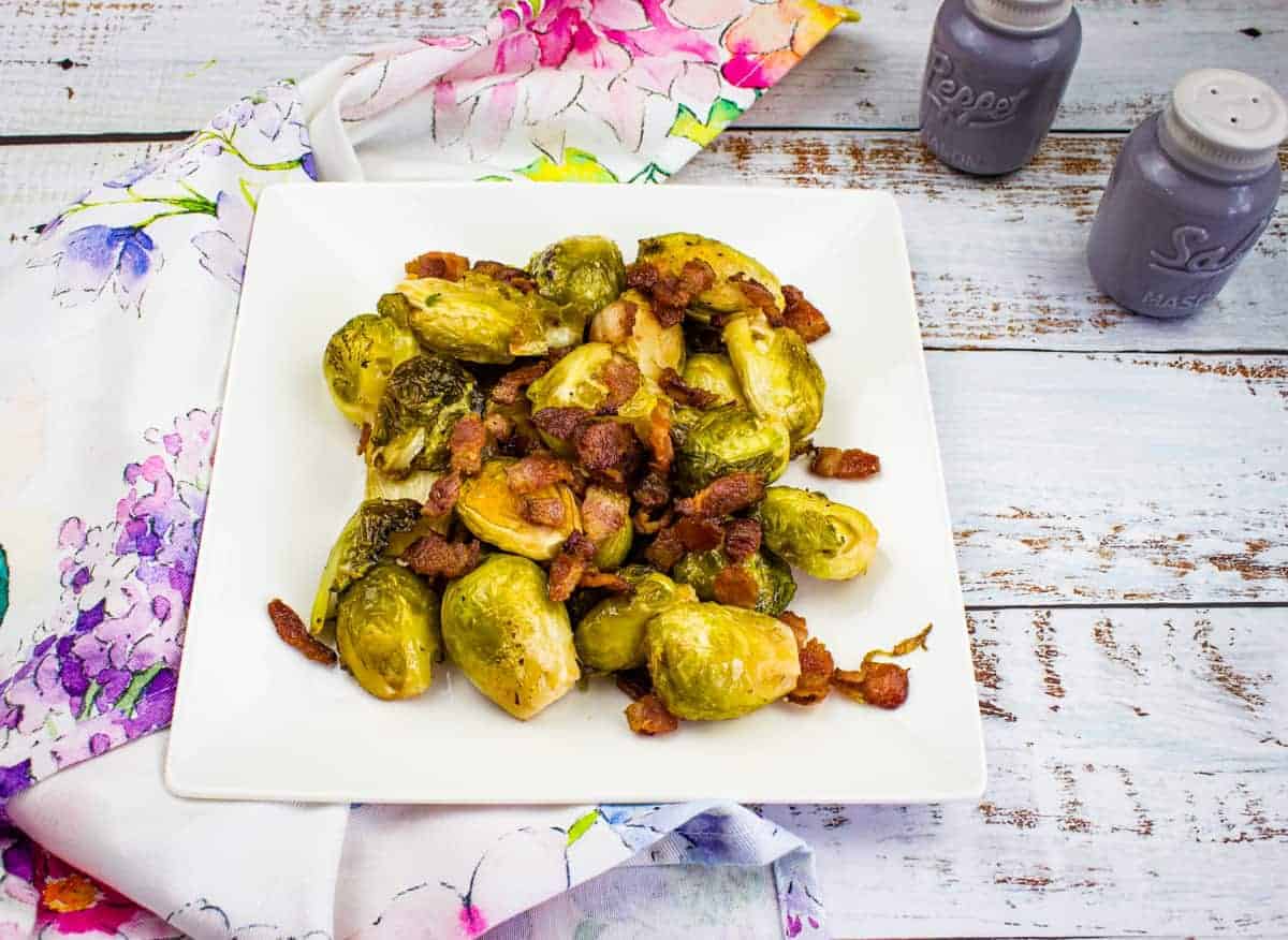 Smoked Brussels Sprouts with bacon on a white plate.