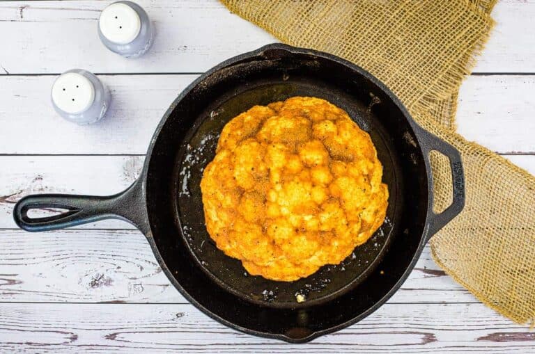 Smoked cauliflower in a skillet on a wooden table.