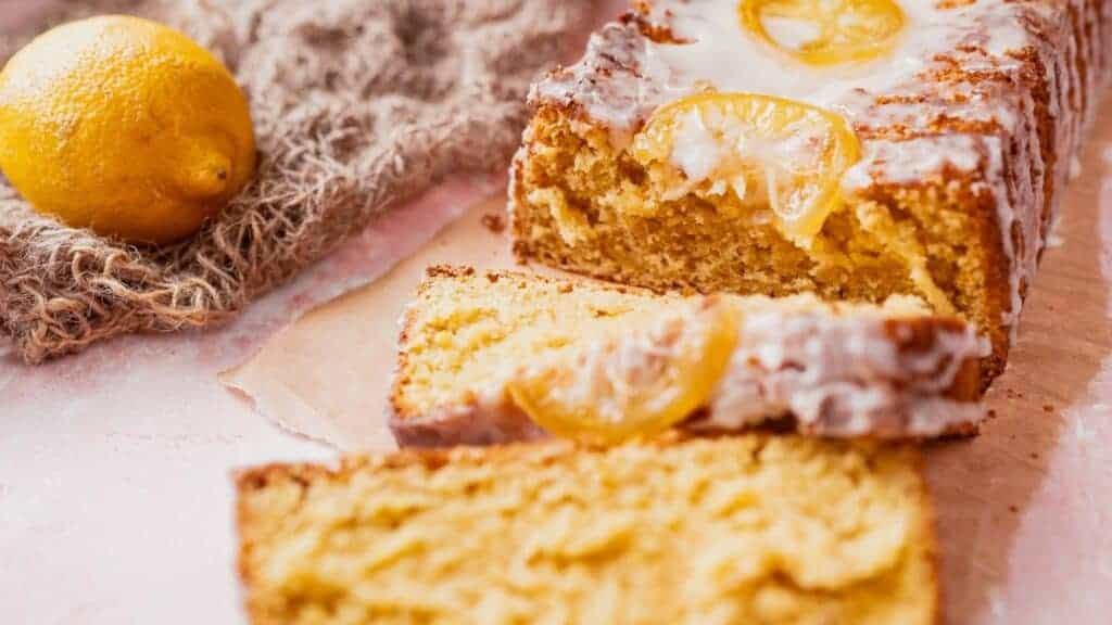 A slice of lemon cake on a pink background.