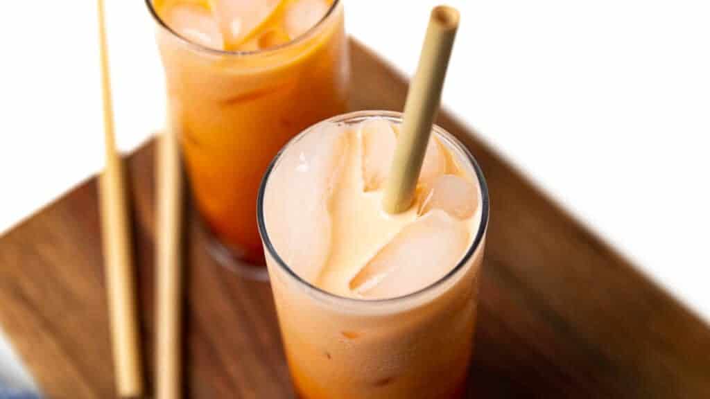 Two glasses of orange liquid with straws.