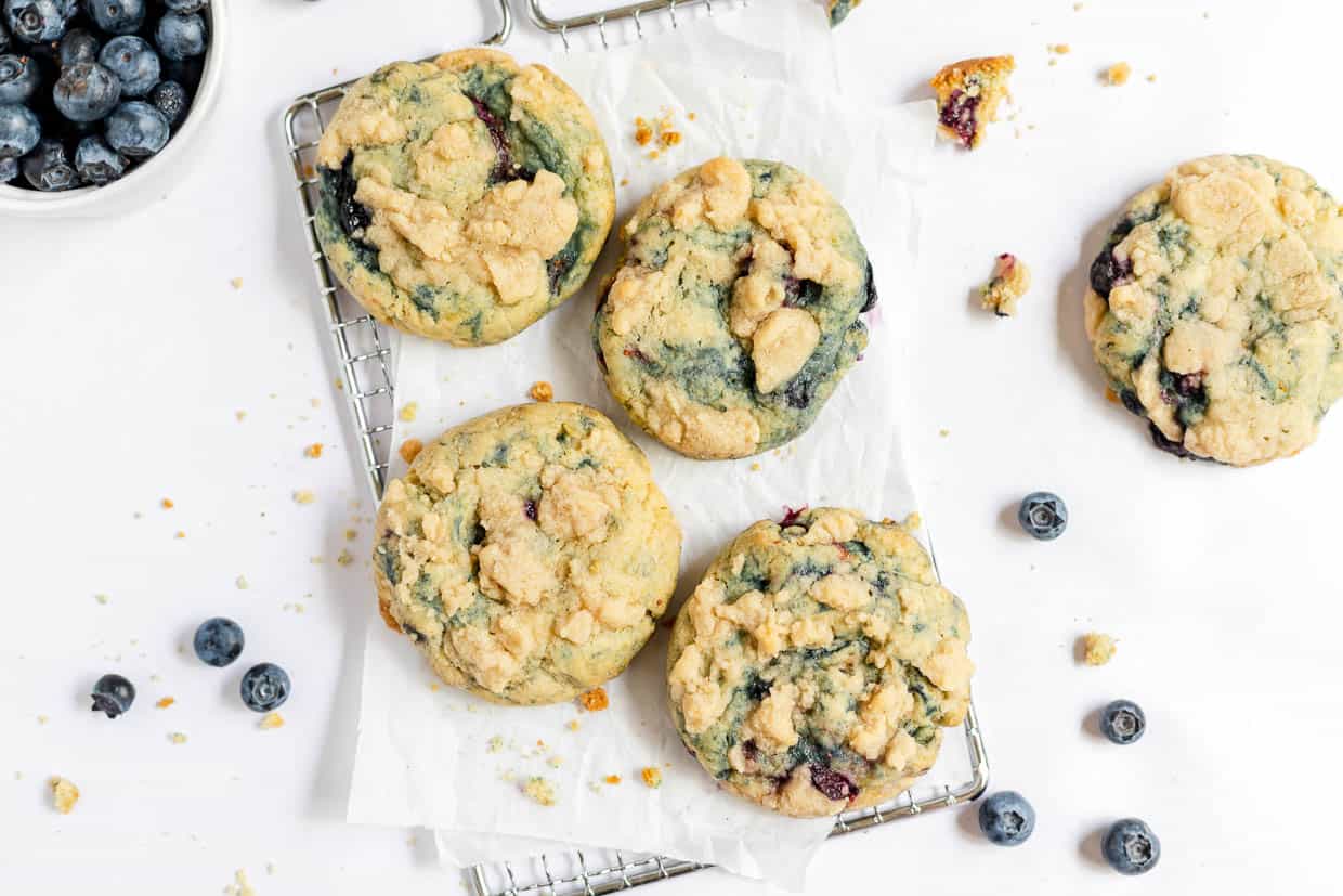 Blueberry cookies on a baking sheet with blueberries.