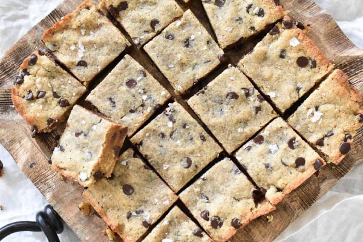 Chocolate chip cookie bars sliced and arranged on a wooden board.