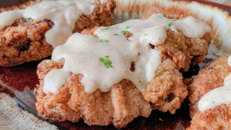 Fried chicken with creamy gravy on a plate.