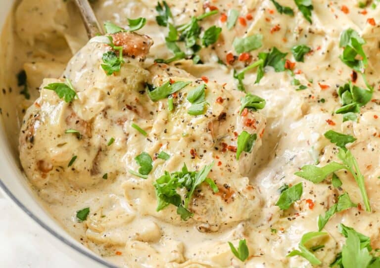 Creamy chicken dish garnished with herbs and spices.