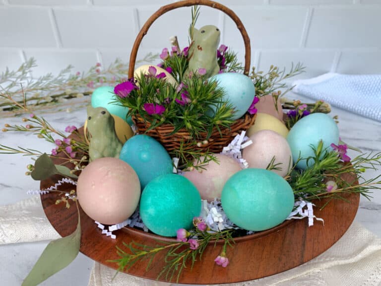 Colorful easter eggs in a basket on a wooden table.