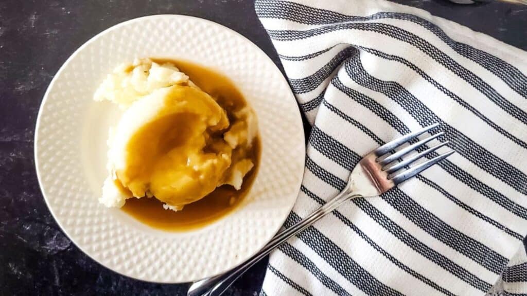 Mashed potatoes with gravy on a plate.