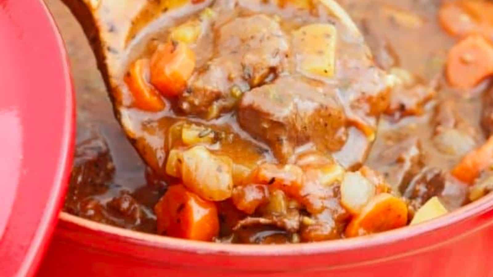 Venison stew in a red pot with a wooden spoon.