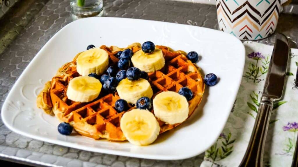 Waffles with bananas and blueberries on a plate.