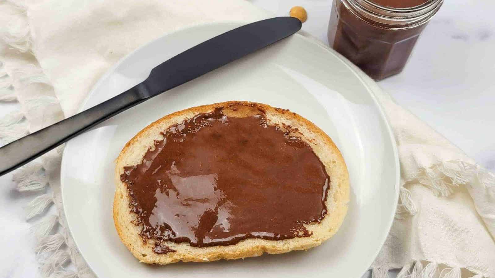 A slice of bread with dairy free chocolate hazelnut spread on it.
