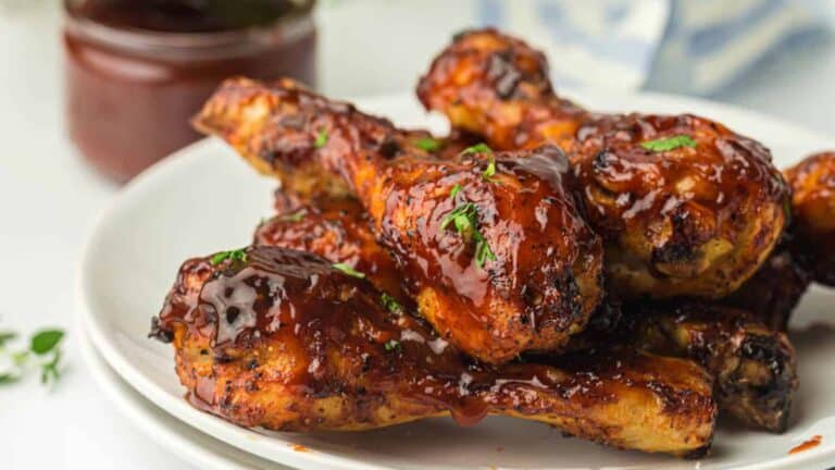 Barbecued chicken drumsticks glazed with sauce on a white plate.