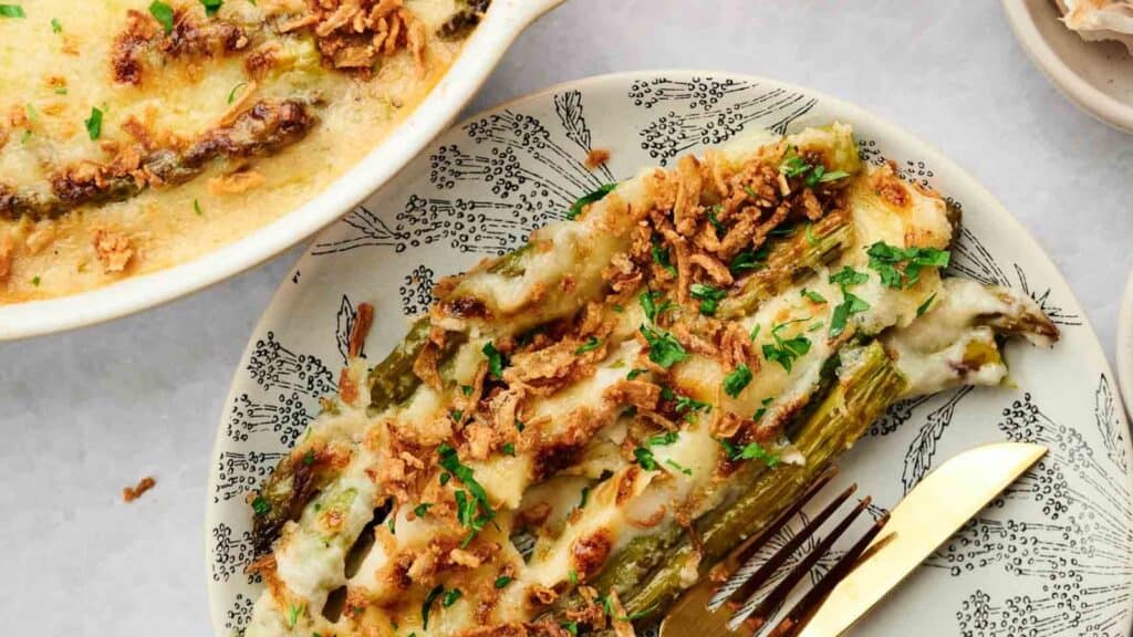 A dish of baked green bean casserole topped with crispy onions and garnished with chopped herbs.