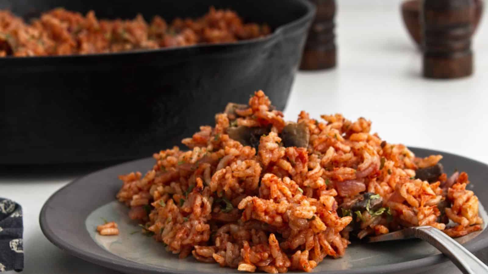 A plate of mushroom baked rice served next to a cast iron skillet.