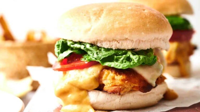 Chicken burger with lettuce, tomato, and sauce on a white background.